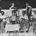 Ορθιος με την κιθάρα ο Γιάννης Σταμούλης ή Μπιρ Αλάχ. Καθιστοί απ'τα αριστερά: Απόστολος Χατζηχρήστος, Λ.Γουναρόπουλος και Μήτσος Μπατάγιας (με την κιθάρα). Πειραιάς 1945.